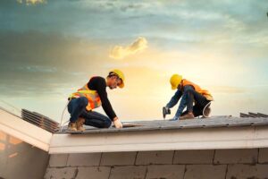 A roof cricket rises behind a chimney, directing rainwater toward metal flashing and roof drainage paths.