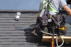 Homeowner reviews roof damage with a roofing inspector beside a ladder and written repair notes.