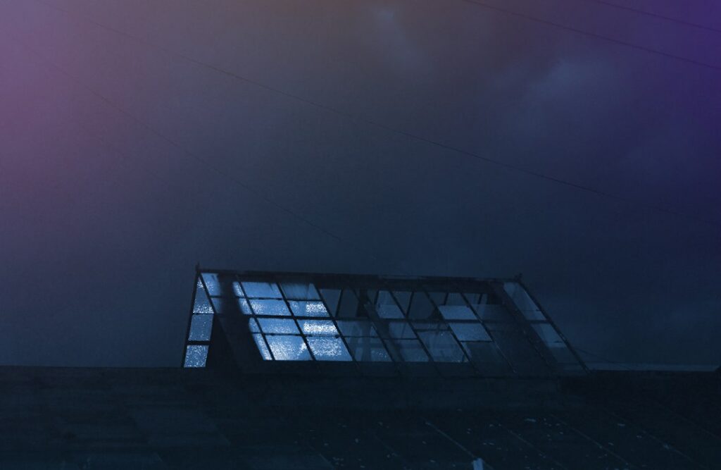 Rain falls on a residential roof above an insulated attic while water flows through a secured gutter and downspout.